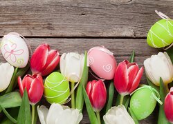 Białe i czerwone tulipany z pisankami na deskach