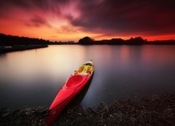 Czerwony kajak na jeziorze o zachodzie słońca