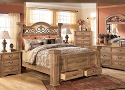 Drewniane łóżko w sypialni obok komody i toaletki