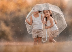 Dzieci chowają się przed deszczem pod parasolem