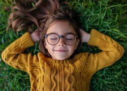 Dziewczynka w okularach leżąca na trawie