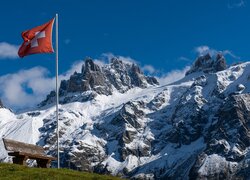 Flaga Szwajcarii obok ławki na tle ośnieżonych Alp