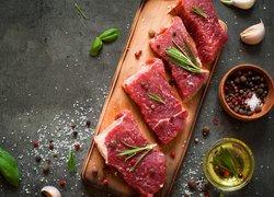 Kawałki surowego mięsa z przyprawami na desce