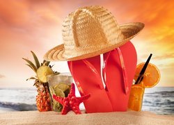 Klapki i kapelusz na plaży obok drinków i ananasa