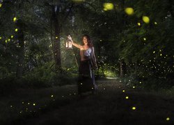 Kobieta z lampionem pośród drzew