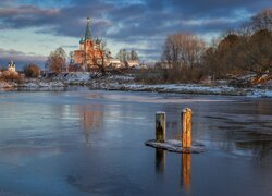Kołki w jeziorze i cerkiew w oddali w zimowej scenerii