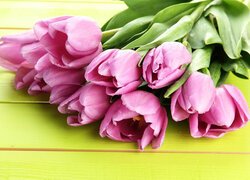 Krople na różowych tulipanach na żółtych deskach