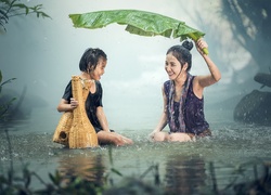 Radosna kobieta i dziecko w rzece podczas deszczu