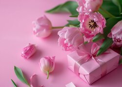 Różowy prezent z kokardą i tulipany na różowym tle