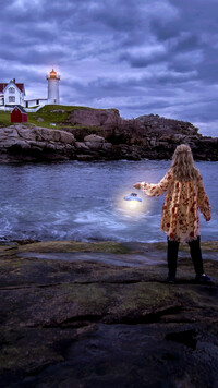 Kobieta z lampą i latarnia morska na skale