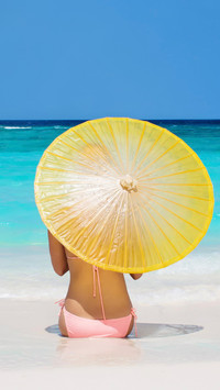 Kobieta z parasolką na letniej morskiej plaży