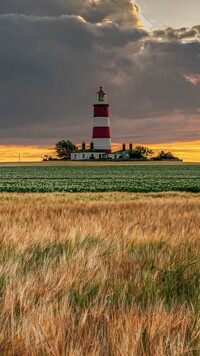 Latarnia morska Happisburgh Lighthouse i pola pod ciemnymi chmurami