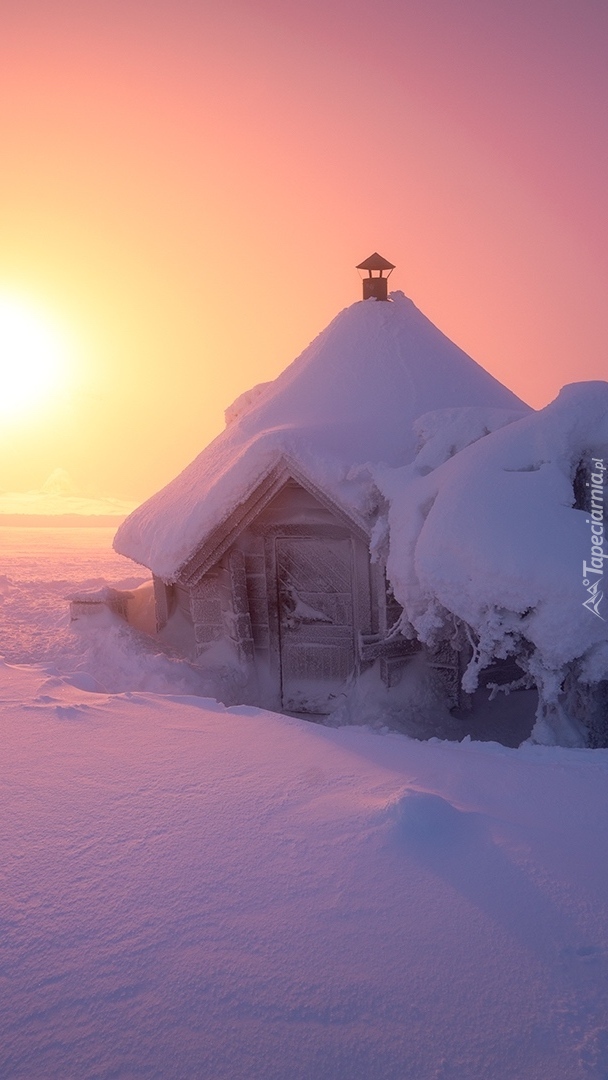 Ośnieżona chata o wschodzie słońca