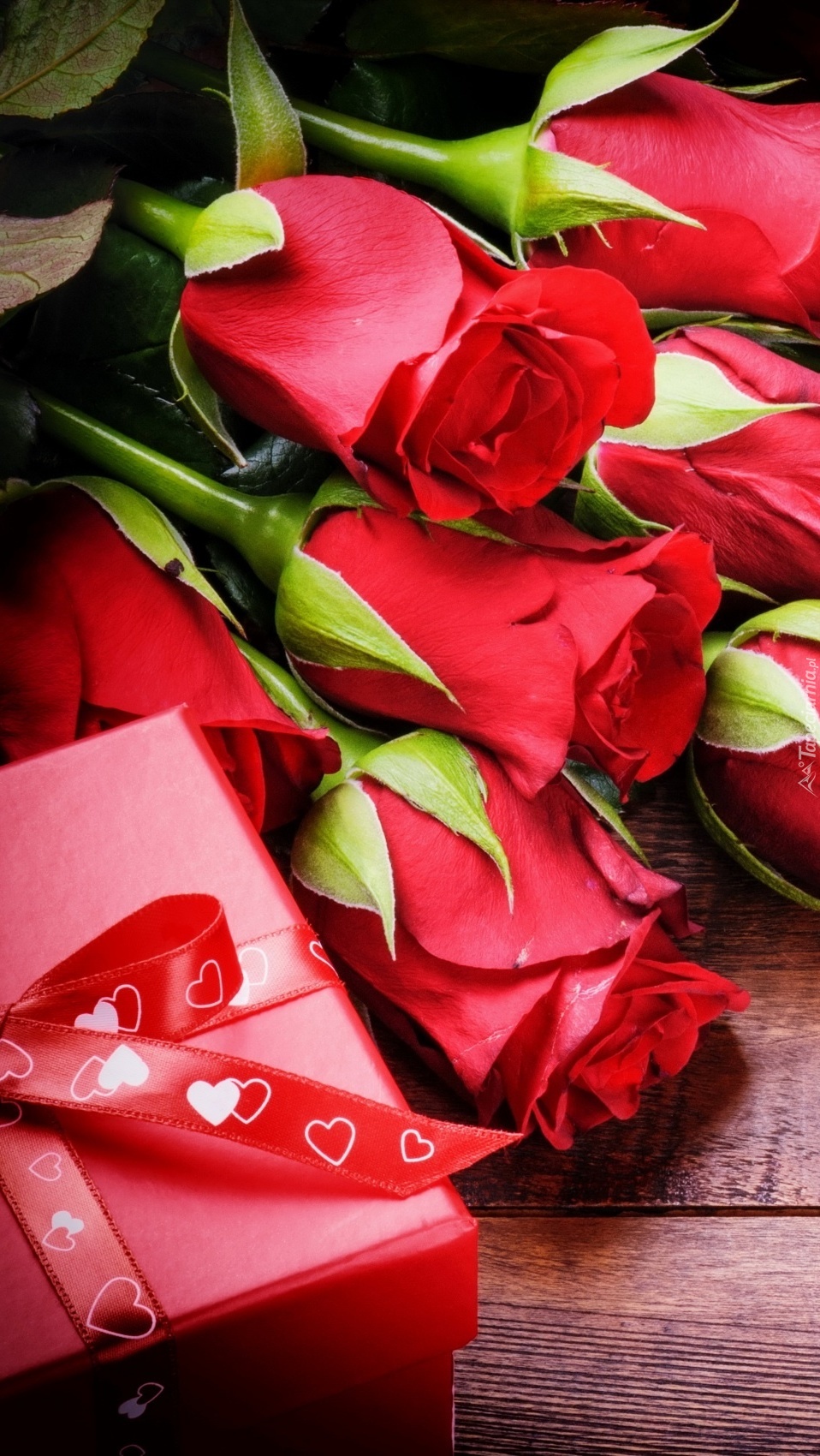 Pudełko z prezentem i czerwone róże na desce