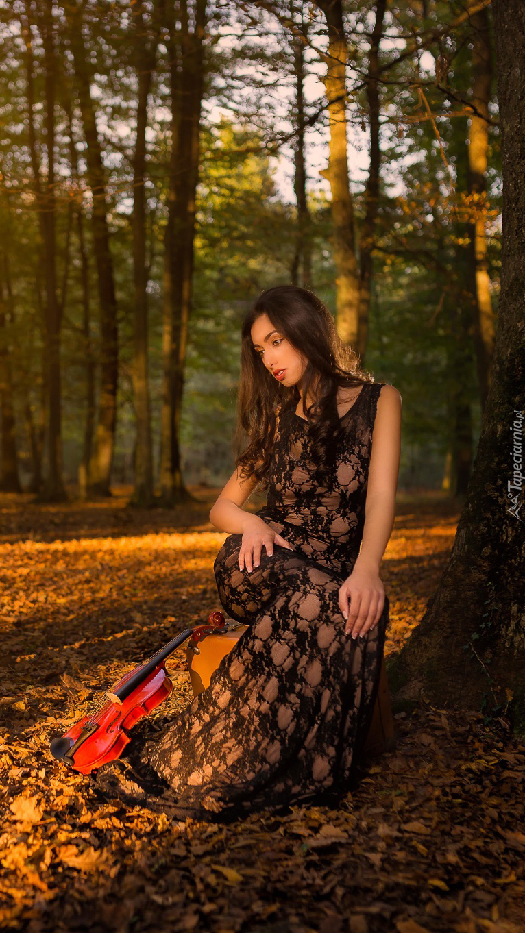 Siedząca kobieta ze skrzypcami pod drzewem