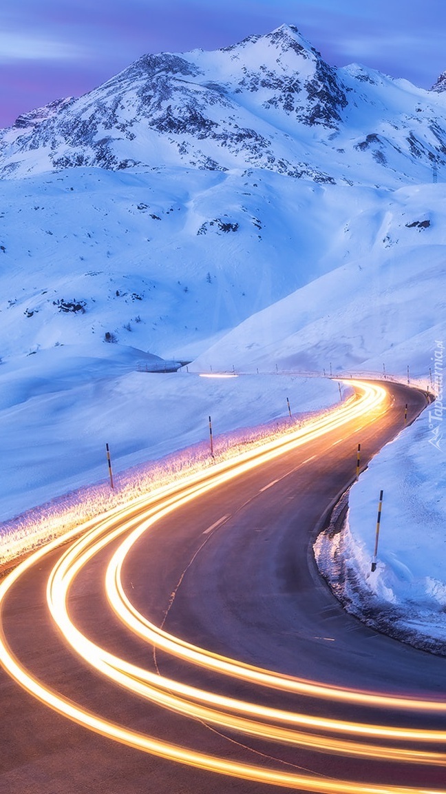 Światła na krętej drodze w zimowych górach