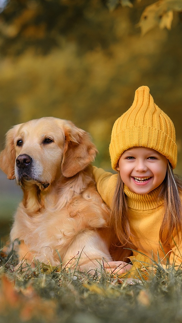 Uśmiechnięta dziewczyna w żółtej czapce i swetrze obok golden retrievera