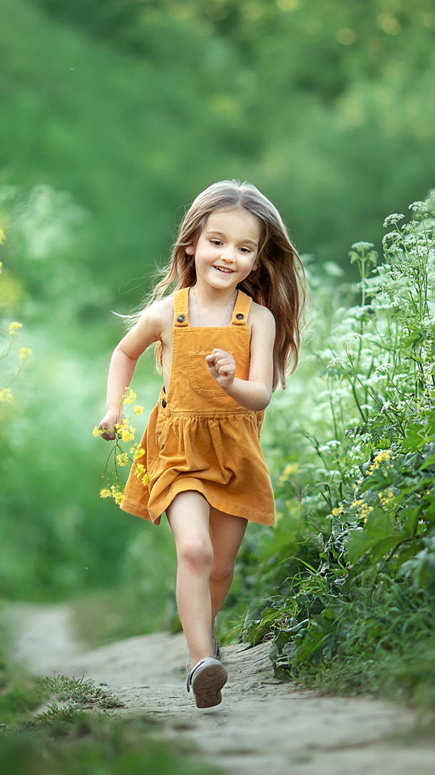 Uśmiechnięta dziewczynka biegnąca ścieżką