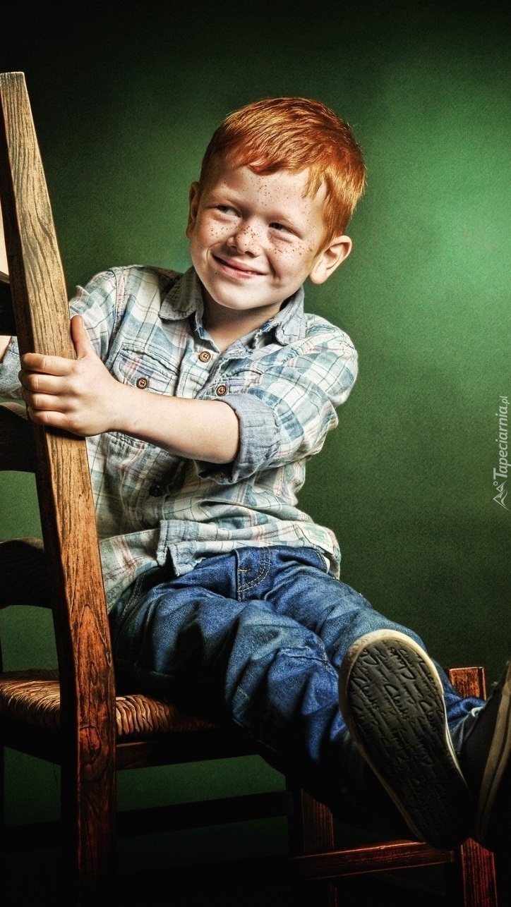 Uśmiechnięty rudy chłopiec na krześle