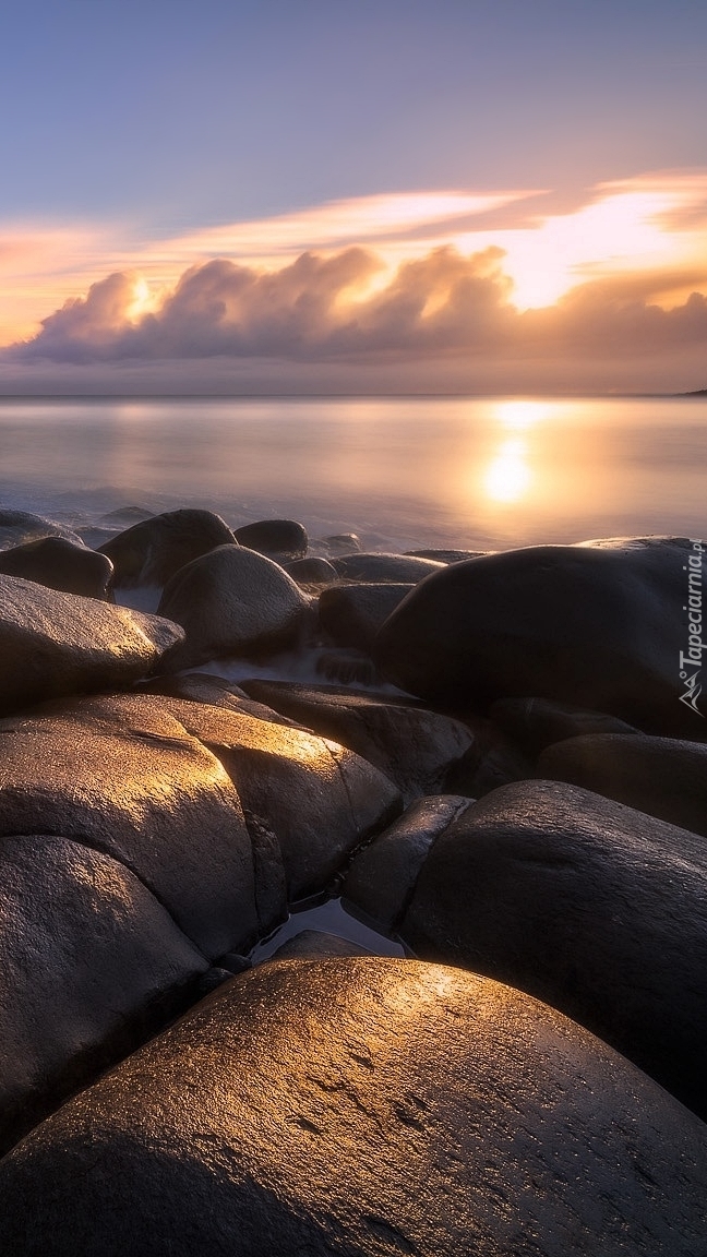 Wschód słońca nad morzem o kamienistym brzegu