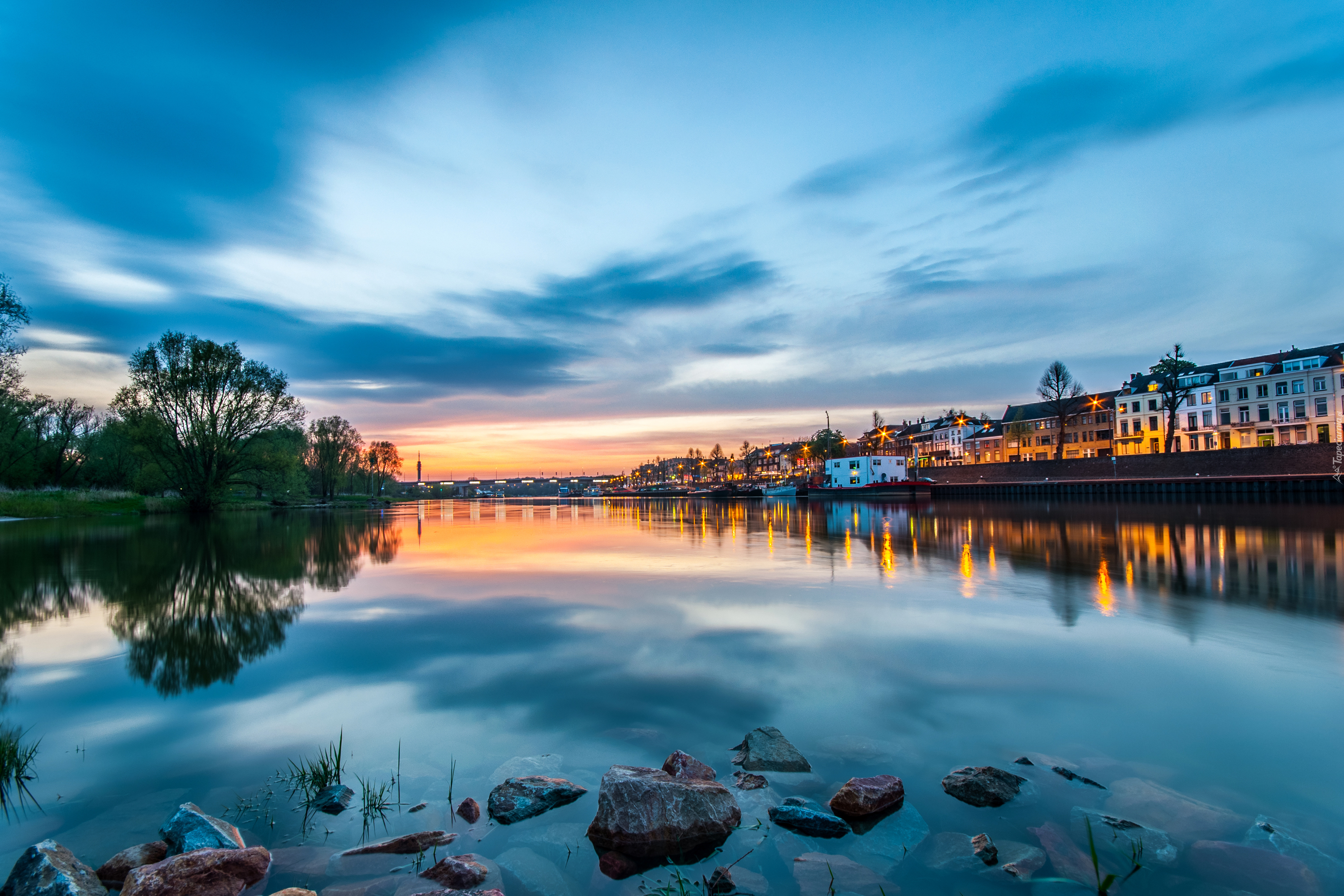 Holandia, Arnhem, Rzeka Ren, Zachód słońca, Drzewa, Budynki, Światła, Odbicie