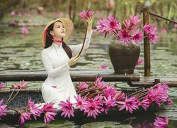 Azjatka w kapeluszu wśród lilii wodnych