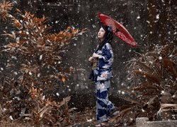 Azjatka w kimonie z parasolem w padającym śniegu