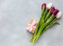 Białe i bordowe tulipany obok prezentu