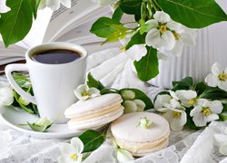 Białe kwiaty obok kubka z kawą i makaroników