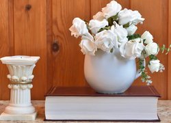 Białe róże w wazonie na książce