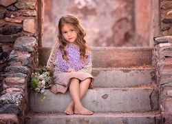 Bosonoga dziewczynka z bukietem kwiatów siedzi na schodach