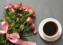 Bukiet róż ze wstążką obok filiżanki kawy