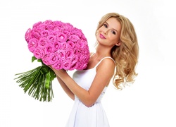 Bukiet różowych róż w dłoniach uśmiechniętej blondynki