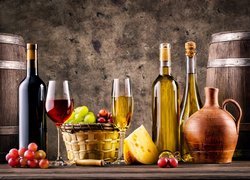 Butelki wina obok sera i kosza z winogronem