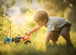 Chłopczyk bawi się samochodem zabawką w trawie