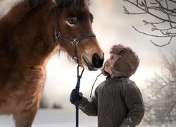 Chłopiec trzymający konia za uzdę