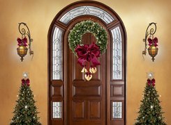 Choinki i latarnie przy świątecznie udekorowanych drzwiach