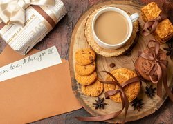 Ciasteczka i kawa na desce obok listu i prezentu