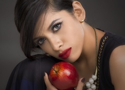 Ciemnowłosa kobieta z czerwonym jabłkiem w dłoni