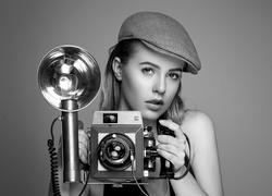 Czarno-białe zdjęcie kobiety w czapce z aparatem fotograficznym