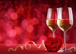 Czerwona róża między kieliszkami z winem
