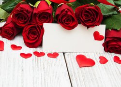 Czerwone róże i serca obok koperty