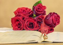 Czerwone róże z obrączkami na książce