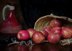 Czerwony dzbanek obok koszyka z jabłkami