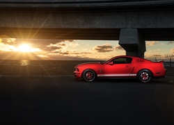 Czerwony Ford Mustang GT 500 pod mostem w promieniach słońca
