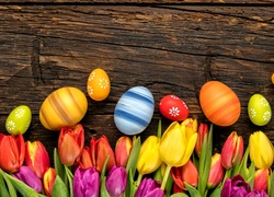 Dekoracja z wielkanocnych pisanek i kolorowych tulipanów na blacie