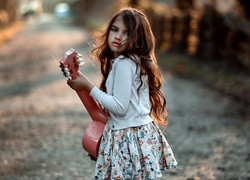 Długowłosa dziewczynka z gitarą na drodze