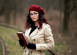 Długowłosa kobieta w berecie i płaszczu z książką