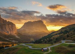 Dom przy drodze w dolinie na tle rozświetlonych Dolomitów