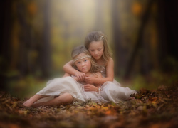 Dwie dziewczynki usiadły na liściach w lesie